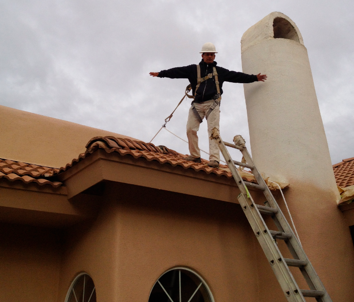 Man on roof top with arms out